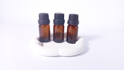 three brown glass bottles with small black screw caps placed on a white textured surface.