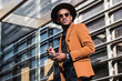 © BUDDHA - A young businessman in the city, on the move, a man in orange suit, holding a mobile phone