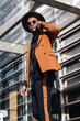 © BUDDHA - A young businessman in the city, on the move, a man in orange suit, holding a mobile phone