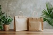 © Jenjira - Two eco-friendly paper bags on a wooden table with greenery in the background.