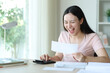 © Antonioguillem - Excited asian woman calculating checking bill