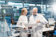 © Westend61 - Two technicians wearing lab coats looking at plan