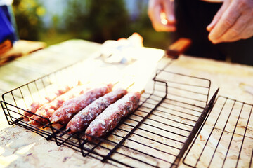 Wall Mural - Selective focus. Cooking barbecue on the mangal in nature. Grilled tasty meet cooking on the party. Traditional Russian shashlik on a barbecue skewer on sunny forest.