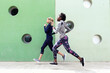 © Westend61 - Two sporty young women running together in the city passing wall with round windows