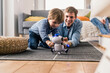 © Westend61 - Father and son lying on floor, playing with toy robot
