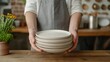 © musa - Person in apron holding a stack of plates.