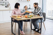 © sofiko14 - Caucasian family with father, mother, and daughter clinking glasses during breakfast. Happy mealtime in bright kitchen setting with fresh food and orange juice. Family bonding and morning routine.