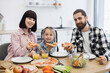 © sofiko14 - Caucasian family with parents and daughter having breakfast with pizza. Family smiles while dining together in bright kitchen, showing happiness and togetherness.