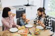 © sofiko14 - Caucasian family of three, parents and child, sharing pizza for breakfast at home kitchen table. Joyful morning scene with family interaction and delicious food.