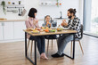 © sofiko14 - Caucasian family of three having breakfast with pizza and fresh fruits at home. Smiling parents and daughter enjoying meal together. Bright kitchen setting with casual attire and relaxed atmosphere.
