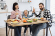 © sofiko14 - Caucasian family of three enjoying breakfast at home. Young daughter gives high five to father. Bright morning scene with happiness and togetherness.