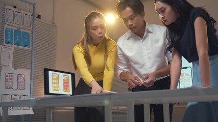 Wall Mural - young asian developers collaborating on mobile app prototype, reviewing design sketches and discussi