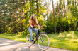 © maxbelchenko - Happy woman riding bicycle bike on sidewalk in city green park outdoors. Active lifestyle concept.