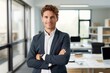 © nsit0108 - Portrait of a smiling young businessman standing with arms crossed in a modern office, exuding confidence and professionalism