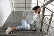 © New Africa - Woman with injured back on stairs in building after fall. Dangerous accident