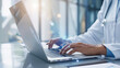© Vilaysack - medical professional typing on laptop in bright office, showcasing telemedicine technology and online healthcare services. scene emphasizes modern healthcare solutions