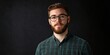 © StockKing - Young professional man with glasses in a checkered shirt against a dark background, offering ample space for text or graphics on the left.