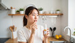 © ON - Studio - Young Asian woman contemplating antihistamines in modern kitchen, seasonal relief