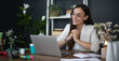 © My Ocean studio - A smiling woman in a white blazer sits at her desk, working on a laptop. She is surrounded by office supplies, a plant, and a cup, giving off a professional, productive vibe in a modern workspace.