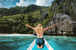 © EVERST - Woman tourist traveling in Philippines, girl happy raised hands on the boat island hopping tour enjoying sea and mountains view active summer vacations explore Palawan tropical vibes healthy lifestyle