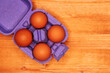 © Bits and Splits - Four chicken eggs in violet cardboard box on the table