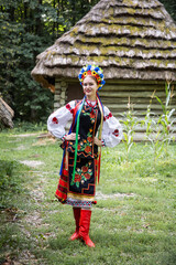 Wall Mural - Woman in traditional costume. Ukrainian woman near the old house. A young woman in a national Ukrainian costume. Embroidery. Ukrainian national clothing.