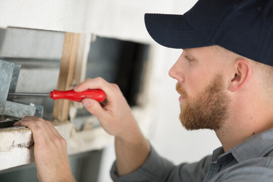 contractor looking at window roller shutter mechanism