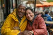 © Markus Schröder - Portrait of a cheerful multiethnic couple in their 70s wearing a lightweight packable anorak isolated on bustling city cafe