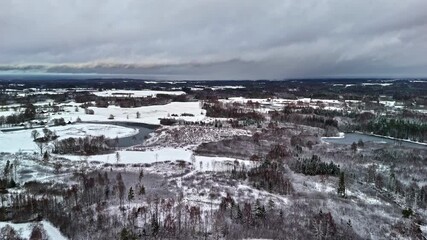 Wall Mural - A snowy aerial landscape with fields, frozen rivers, and sparse trees under a cloudy sky