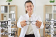 © Studio Romantic - Positive female ophthalmologist holds eyeglasses, representing optometry and eye care. Doctor optometrist provides healthcare attention and expertise in ophthalmology for patient eye health.