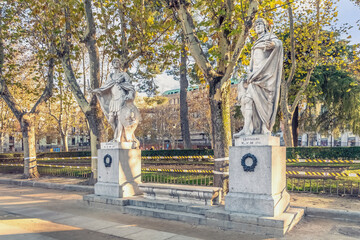 Marble statues of Suintila and Leovigildo, two ancient kings of Spain, stand tall in Plaza de Oriente, Madrid. Detailed sculptures are surrounded by autumn foliage. Madrid, Spain - November 30, 2021