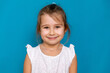 © Irina Mikhailichenko - Adorable five-six years old girl in white t-shirt or summer dress isolated on blue background, pretty brown-haired european appearance child pose indoor, smiling, look at camera, generation Z concept