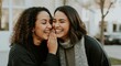 © Artyom - Two women smiling and whispering outdoors in winter attire
