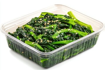 Wall Mural - Korean spinach side dish in a plastic container on a white background Spinach is blanched and flavored with soy sauce garlic and sesame oil