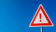 © Fatima - A blank white triangular warning sign with an exclamation mark highlights caution against a vibrant blue backdrop during a sunny day