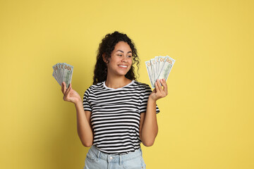 Wall Mural - Happy woman with dollar banknotes on yellow background