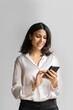 © Stock 4 You - Smiling young middle eastern businesswoman using smartphone mobile phone online ai app for work isolated on white background. Latin woman it specialist in business suit holding cellphone. Vertical