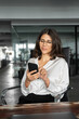 © Stock 4 You - Vertical portrait it specialist business woman manager ceo using cell phone mobile ai app for online work. Focused Latin Hispanic female businesswoman holding smartphone sitting at desk in office