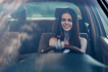 Canvas Print - Beautiful young woman smiling while driving a car, showcasing confidence and joy in a summer setting, highlighting a sense of adventure and freedom.