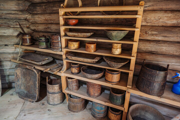 Displaying traditional russian wooden kitchenware, including bowls, buckets, and troughs, on rustic log cabin shelves