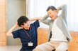© buritora - リハビリで体操をするシニア男性と理学療法士・作業療法士の男性スタッフ
