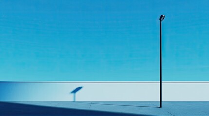 Wall Mural - minimalist street lamp casting a long shadow under a clear blue sky, evoking simplicity and elegance