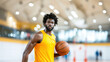 © tashechka - Focused male basketball player wearing a bright yellow jersey, holding a ball, standing in a modern sports gym setting.