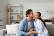 © Pixel-Shot - Happy husband kissing his wife on sofa at home