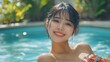 © The 2R Artificiality - Beautiful young Asian woman smiling joyfully in a vibrant swimsuit, relaxing by a tranquil blue swimming pool at a resort hotel surrounded by lush greenery.