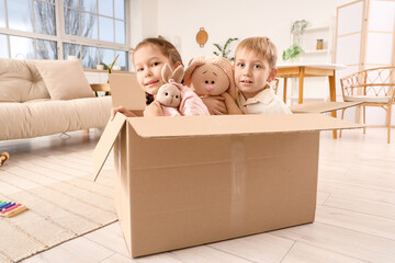 Canvas Print - Cute little children with knitted toys playing in cardboard box at home