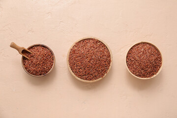 Wall Mural - Wooden bowls with raw brown rice and scoop on beige background