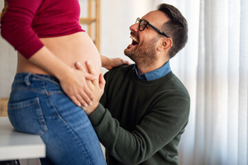 Wall Mural - Beautiful pregnant woman and her handsome husband are smiling while spending time together