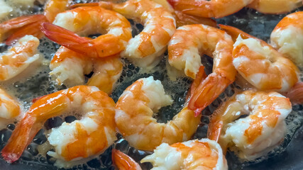 Succulent shrimp sizzling in a pan evoke summer seafood grilling, perfect for festive gatherings and culinary enthusiasts