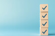 © Towhid Art Mart - Checklist concept. Correct sign tick check mark on wooden block with copy space for the checklist on blue background. Business survey questionnaire, Exam test process
